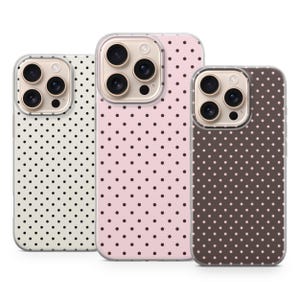 Può includere: Tre custodie per telefono con un motivo a pois. Una custodia è bianco sporco con pois neri, un'altra è rosa con pois rosa scuro e la terza è marrone con pois rosa chiaro. Le custodie hanno un bordo trasparente e un ritaglio per la fotocamera.