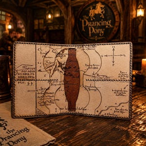 Puede incluir: Cartera de cuero abierta con diseño de mapa y forma de botella marrón en el centro. El logo 'The Prancing Pony' es visible en un posavasos. Ambiente de pub con una vela encendida.