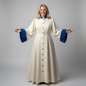 May include: A cream-colored robe with blue accents. The robe features a high collar, blue buttons, and wide sleeves with blue cuffs. The long, flowing garment is buttoned down the front and is worn by a person.