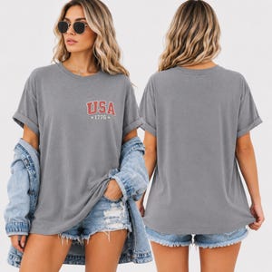 Designed with a classic Americana aesthetic, this patriotic USA graphic shirt features a bold vintage American flag print alongside “Land of the Free” typography for a timeless patriotic statement. Whether worn during Independence Day events, summer road trips, patriotic celebrations, Memorial Day gatherings, or everyday casual wear, this comfortable t-shirt brings together retro style and American pride in one fashionable design perfect for women who love vintage patriotic apparel.