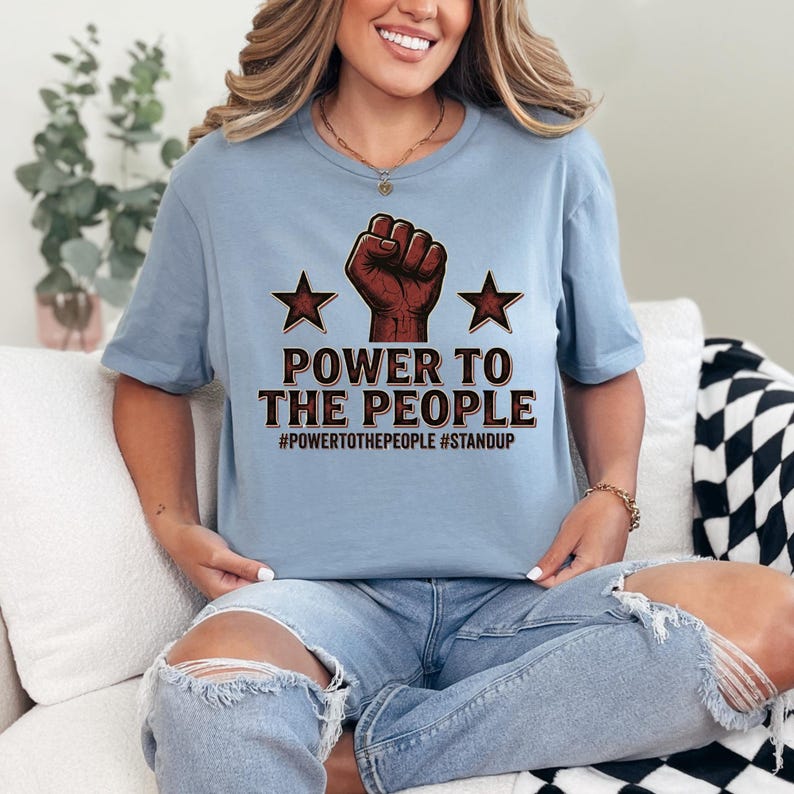 The design highlights the iconic raised fist symbol, long associated with solidarity and resistance movements around the world. Paired with bold lettering and star elements, the graphic creates a powerful visual statement that blends modern streetwear aesthetics with classic protest imagery.