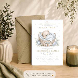 Könnte beinhalten: Eine Geburtsanzeigekarte mit einem Teddybären, der in einem geflochtenen Korb mit einer blauen Decke schläft. Der Text enthält CONGRATULATIONS ON YOUR BEAUTIFUL GRANDSON, THEODORE JAMES, Geburtsdaten sowie 3,42 kg und 52 cm.