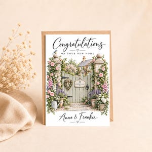 May include: A greeting card featuring the text Congratulations On Your New Home and Anna & Frankie. The illustration shows a light green wooden gate with a sign reading 32 Woodmill Lane, surrounded by pink roses, purple flowers, and a small bird.