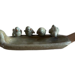 May include: A long, shallow ceramic tray with a glossy tan glaze. The left end is shaped like a bird head, while the right end features a textured, fan-shaped tail. Four small, round ceramic birds are perched along the inner rim of the tray.