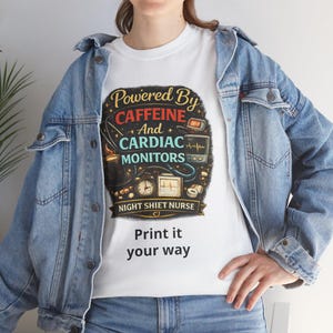 Puede incluir: Camiseta blanca con un diseño gráfico que presenta el texto "Powered By Caffeine And Cardiac Monitors" y "Night Shift Nurse". El diseño incluye imágenes de una taza de café, un reloj y un monitor cardíaco. Debajo del diseño está el texto "Print it your way".