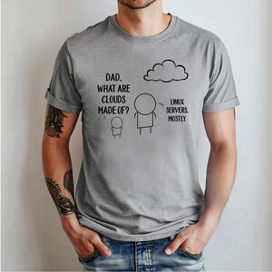 Op de afbeelding: Een lichtgrijs t-shirt met een humoristische afbeelding. De afbeelding toont stokfiguren, een wolk en de tekst: "Papa, waar zijn wolken van gemaakt?" en "Linux-servers, meestal."