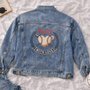 Peut inclure: Veste en jean bleu clair avec un motif sur le thème du baseball au dos. Le motif représente un ballon de baseball en forme de cœur avec les mots "PLAY WITH LOVE". Comprend des baskets blanches et des lunettes de soleil.