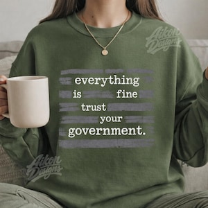 Puede incluir: Una taza de cerámica blanca con asa negra y el texto "But First, Coffee" en negrita negra. La taza está sobre una superficie de madera.