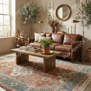 Puede incluir: Un salón con un sofá de cuero marrón, una mesa de centro de madera y una alfombra estampada con detalles en rojo y azul. La habitación está decorada con plantas, un espejo redondo y lámparas de pie, creando un ambiente cálido y acogedor.