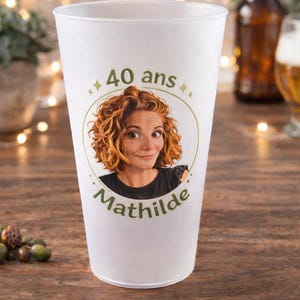 May include: White plastic cup with a photo of a woman with curly red hair. The cup has the text "40 ans" and the name "Mathilde" printed on it. The cup is likely for a birthday celebration.