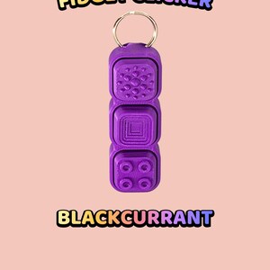 Może przedstawiać: Fioletowy brelok typu fidget clicker z trzema r&oacute;żnymi teksturowanymi przyciskami z wzorem koła, kwadratu i czterech kropek. Tekst "TEXTURED BUTTON FIDGET CLICKER" oraz "BLACKCURRANT" znajduje się odpowiednio nad i pod obiektem.