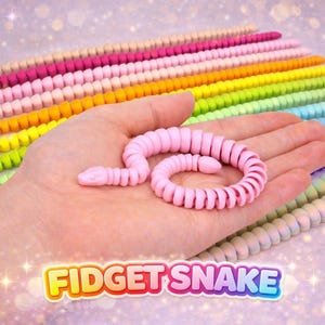 May include: A pink fidget snake toy held in a hand, with a rainbow of other fidget snakes in the background. The toy is made of connected, segmented pieces. The image includes the text "FIDGET SNAKE".