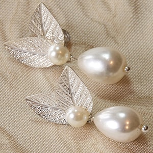 May include: A pair of silver leaf earrings with a pearl drop on each earring.