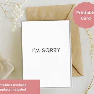 Può includere: Una carta bianca con la scritta "I'M SORRY" in nero, posta su una busta marrone. Un adesivo rosa con "Printable Card" è sulla busta. Un regalo avvolto in carta marrone e legato con spago è sullo sfondo. Le parole "Printable Envelope Template Included" sono in basso.