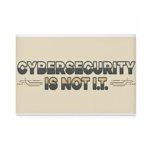 Puede incluir: Un imán rectangular con el texto "CYBERSECURITY IS NOT I.T." en una fuente retro. El texto es negro y gris sobre un fondo beige. Hay diseños de circuitos dorados y negros a ambos lados del texto.