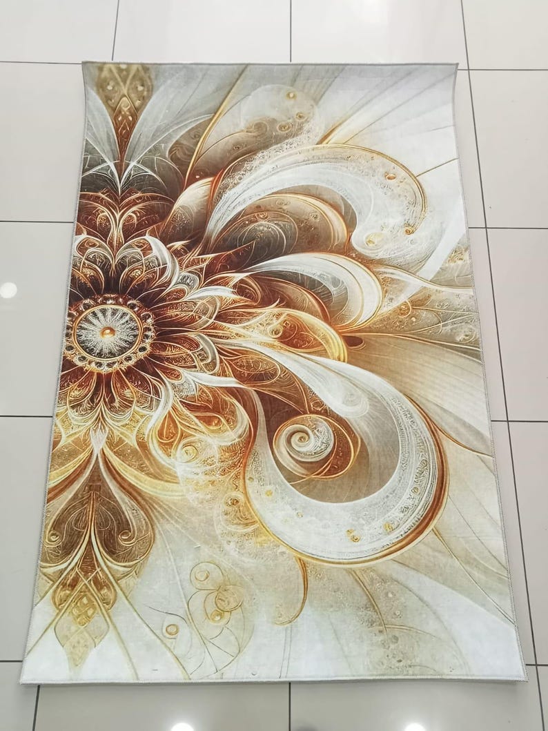 May include: A rectangular rug with a floral design. The rug features a large, stylized flower in shades of brown, gold, and white. The design has intricate details and a swirling, abstract pattern. The rug is placed on a tiled floor.