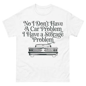 Puede incluir: Camiseta blanca con el texto "No I Don't Have A Car Problem I Have a Storage Problem" y una ilustración en blanco y negro de un coche clásico. La camiseta tiene cuello redondo y mangas cortas.