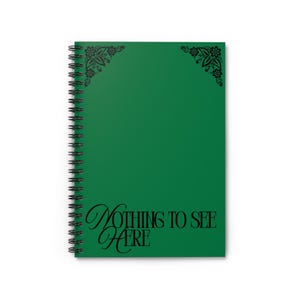 May include: A green spiral-bound notebook with the words "Nothing to See Here" in black script. The cover has decorative floral corner accents. The notebook is designed for writing and note-taking, ideal for use at home or in the office.