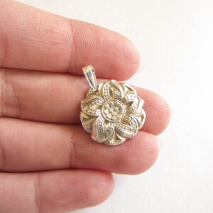 Puede incluir: Pendiente de plata en forma de flor con un dise&ntilde;o detallado. La flor tiene cinco p&eacute;talos y un centro con un patr&oacute;n circular.