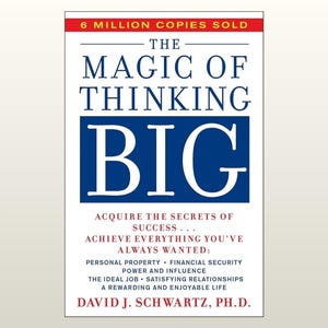May include: A book cover titled The Magic of Thinking Big by David J. Schwartz, Ph.D. The cover features a white background with blue text and a red banner at the top stating 6 Million Copies Sold. It lists various goals like financial security.