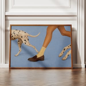 Puede incluir: Una impresión de arte mural rectangular enmarcada que presenta una composición surrealista sobre un fondo azul claro. La imagen muestra un par de piernas con calcetines color canela y mocasines marrones, flanqueadas por los cuerpos blancos manchados de dos perros dálmatas.