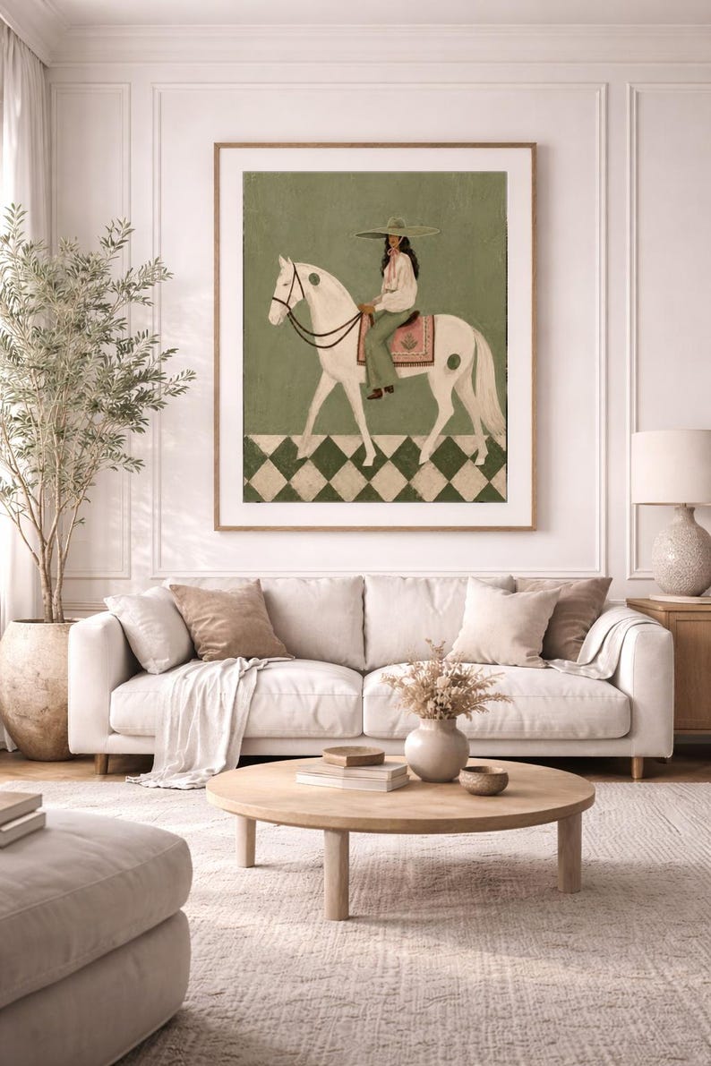 May include: A framed wall art print featuring a painting of a person wearing a wide-brimmed hat and light-colored clothing, riding a white horse. The background is sage green with a checkered pattern at the bottom in dark green and white.