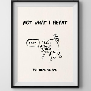 May include: Black framed art print with a whimsical cat illustration. The cat has a surprised expression and a speech bubble that says "oops". The text above the cat reads "NOT WHAT I MEANT", and below it, "BUT HERE WE ARE."