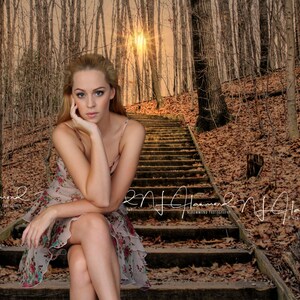 May include: A young woman wearing a floral dress sits on a wooden staircase in a woodland setting. The sun shines through the trees, casting a warm glow on the scene.