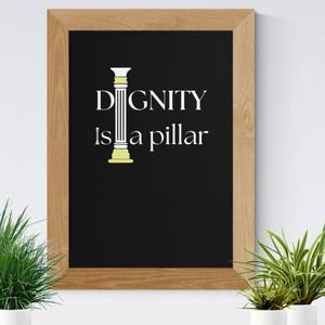 Peut inclure: Impression encadrée avec les mots "DIGNITÉ est un pilier" en texte blanc sur fond noir. Un pilier stylisé est entre les mots. Le cadre est brun clair. Deux plantes en pot sont au premier plan.