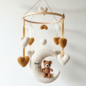 Peut inclure: Mobile pour bébé fait à la main avec un anneau en bois, des cœurs en crochet crème et jaune moutarde, et un croissant de lune crème. Un petit ours en peluche est assis sur la lune.