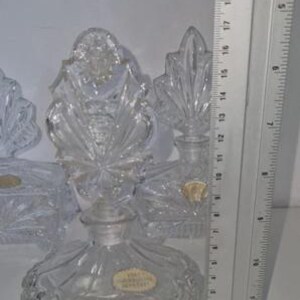 May include: Clear crystal perfume bottle with a round base and a decorative stopper. The bottle is approximately 5 inches tall. The stopper has a starburst design. The bottle has a label that reads "Made in Czechoslovakia".