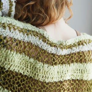 May include: A loose-knit crochet jumper featuring horizontal stripes in varying shades of olive green, light sage, and cream. The garment is constructed with an open, airy stitch pattern that creates a textured, semi-sheer appearance throughout.