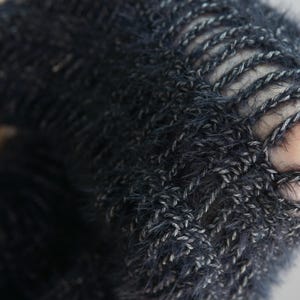 May include: A dark charcoal gray knitted garment featuring a fuzzy, textured yarn construction with an open-stitch pattern. The knit displays a distinct ladder-like design where vertical strands of yarn create elongated gaps throughout the fabric.