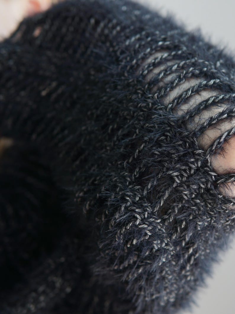 May include: A dark charcoal gray knitted garment featuring a fuzzy, textured yarn construction with an open-stitch pattern. The knit displays a distinct ladder-like design where vertical strands of yarn create elongated gaps throughout the fabric.