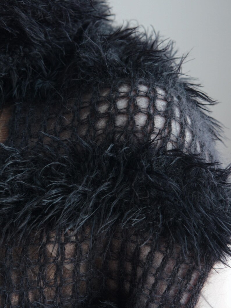 May include: A black knit garment featuring a textured, shaggy, faux-fur-like yarn interspersed with sections of an open, grid-like mesh pattern. The material has a long, wispy pile that creates a dense, layered appearance across the surface.