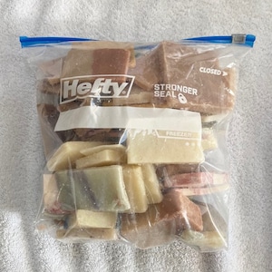 May include: A clear plastic freezer bag filled with various rectangular bars of soap in shades of brown, beige, and green. The bag is labeled "Hefty" and "Stronger Seal".