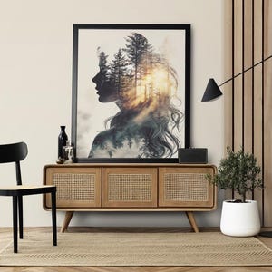 Peut inclure: Une impression d'art encadrée représentant le profil d'une femme avec une forêt en arrière-plan. L'œuvre est au-dessus d'un meuble en bois avec des portes en canne tressée. Une chaise noire, un lampadaire et une plante en pot complètent la décoration.