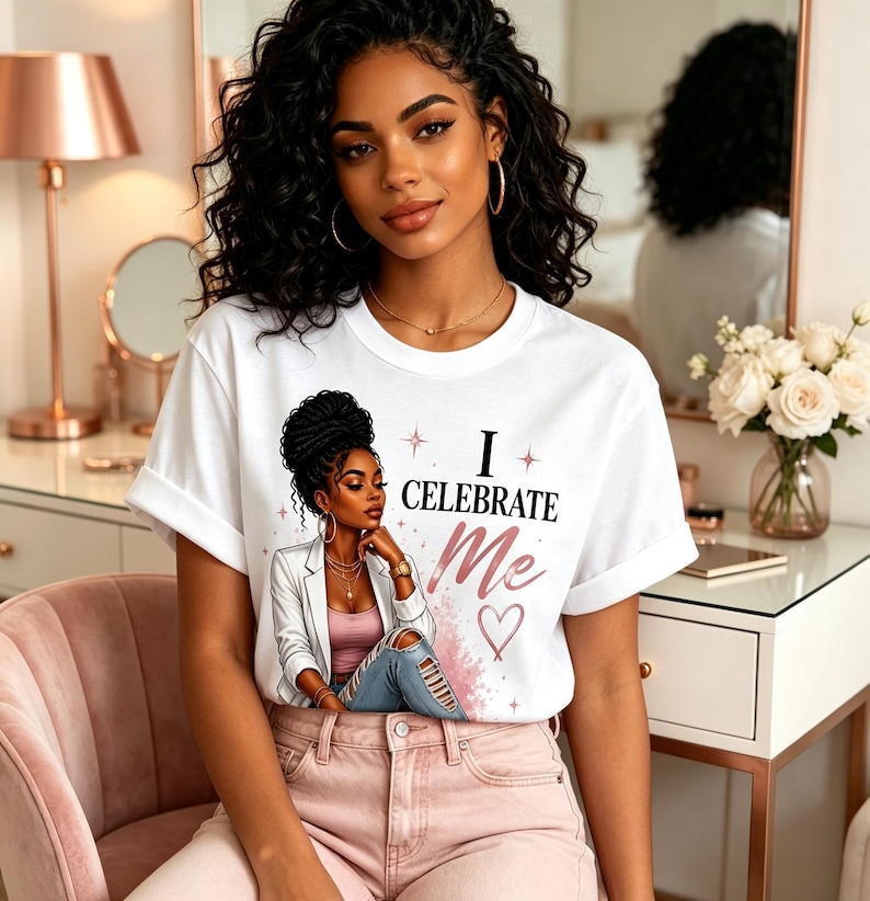 May include: A white short-sleeved t-shirt featuring a graphic illustration of a person with dark curly hair wearing a white blazer and blue jeans. The text "I CELEBRATE Me" is printed in black and pink, accompanied by a pink heart and star accents.