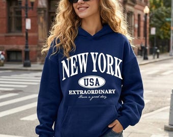 May include: A navy blue hooded sweatshirt featuring white text that reads NEW YORK, USA, EXTRAORDINARY, and Have a good day. The hoodie includes a front kangaroo pocket, long sleeves with ribbed cuffs, and a matching drawstring hood.