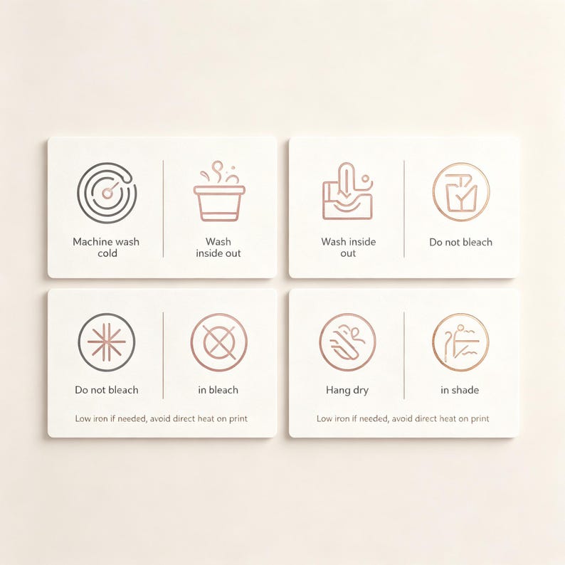 May include: A set of four white rectangular care instruction cards featuring rose gold line art icons and text. The cards display symbols and instructions for machine wash cold, wash inside out, do not bleach, hang dry in shade, and low iron.