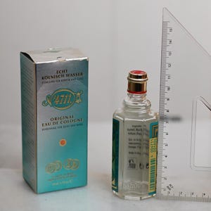 May include: A bottle of 4711 Original Eau de Cologne, with a red and gold cap, next to its teal and silver box. The bottle is approximately 3 inches tall. The box and bottle have text in German.