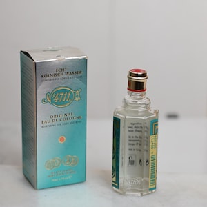 May include: A vintage bottle of 4711 Original Eau de Cologne with its original box. The box is silver and teal with gold accents. The cologne bottle is clear with a red and gold cap. The text "4711" is visible on both the box and the bottle.