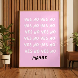 May include: A rectangular wall art print featuring a light pink background with the words YES NO YES NO repeated in six rows using a white, rounded, handwritten font, followed by the word MAYBE in a bold, black, handwritten font at the bottom.