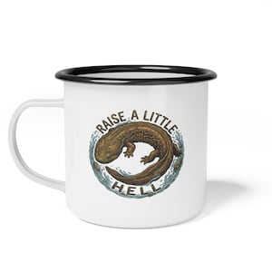 May include: White enamel mug with a black rim and handle. The mug features a brown salamander illustration surrounded by blue water and the text "RAISE A LITTLE HELL" in a circular design. A fun, novelty item.