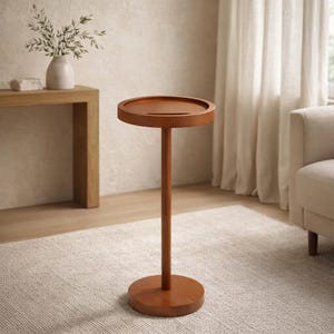 Könnte beinhalten: Ein runder Beistelltisch aus Holz mit dunkelbraunem Finish. Der Tisch hat eine kreisförmige Oberseite mit erhöhtem Rand, getragen von einem schlanken, vertikalen Pfosten und einem runden Sockel. Der Tisch ist etwa 71 cm hoch.