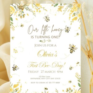 May include: A white invitation card with yellow floral and bee illustrations. The text reads "Our little honey is turning one!" and "Olivia's First Bee-Day!" with event details.
