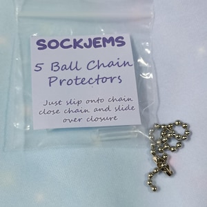 May include: A clear plastic bag containing five ball chain protectors. The label reads "SOCKJEMS" and "5 Ball Chain Protectors." Instructions are printed below. A silver-coloured ball chain is visible.