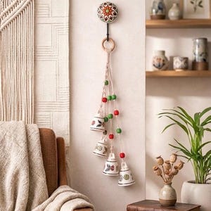 May include: A set of three ceramic mugs with a speckled, cream-colored glaze. Each mug features a different hand-painted floral design in shades of blue, green, and yellow. The mugs have a simple, rounded shape and a comfortable handle.