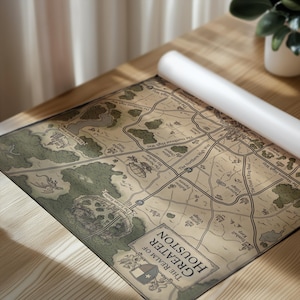May include: A rolled-up map of Greater Houston, featuring a detailed illustration of roads, landmarks, and the text "The Realm of Greater Houston." The map has a vintage aesthetic with a beige background and green and brown details.
