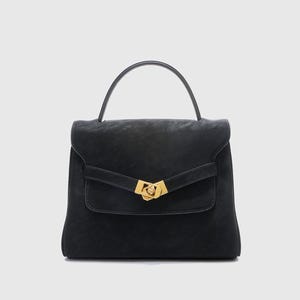 May include: A black handbag with a top handle and a flap closure. The bag features a gold-colored clasp and a small front pocket. The leather bag has a structured design and a minimalist aesthetic.